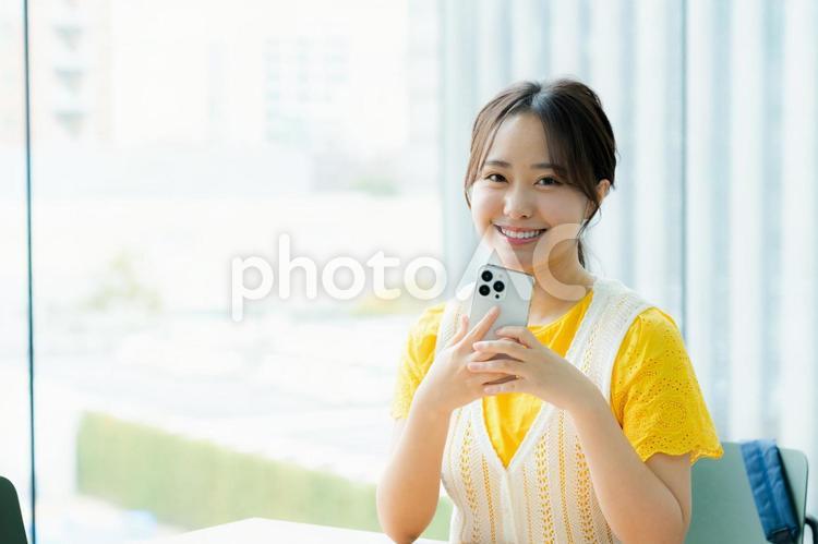 カフェでスマホを見る学生 スマホ,若い女性,笑顔の写真素材