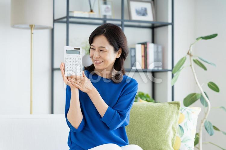 電卓を持つミドルの女性 電卓,計算機,笑顔の写真素材