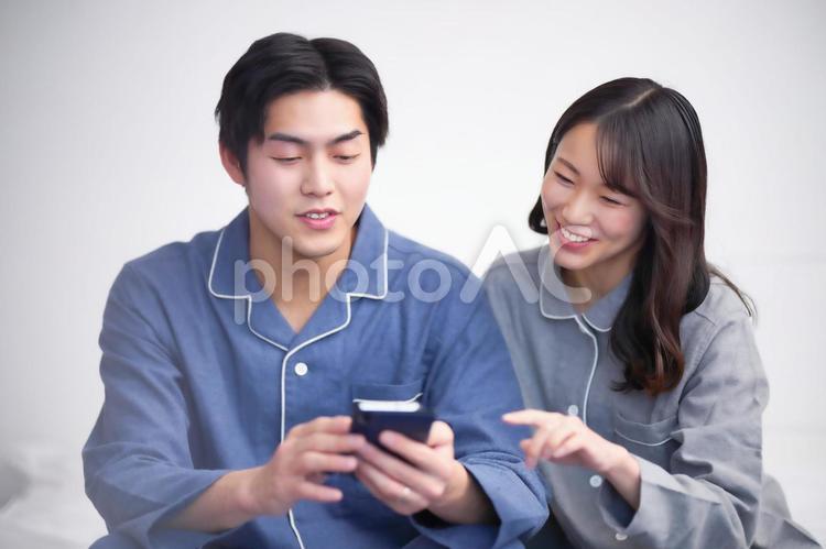 ベッドでスマホを見ているパジャマ姿の夫婦1寝る前 パジャマ,夫婦,カップルの写真素材