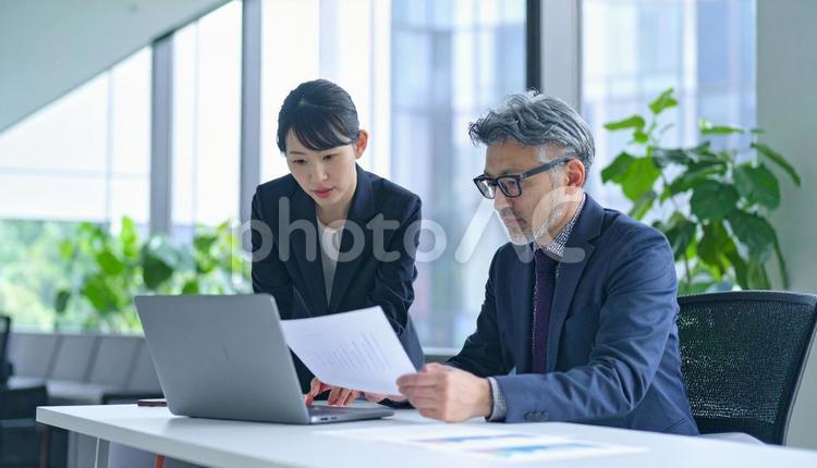 データを見ながら相談する上司と部下 ビジネスマン,ビジネスウーマン,男女の写真素材