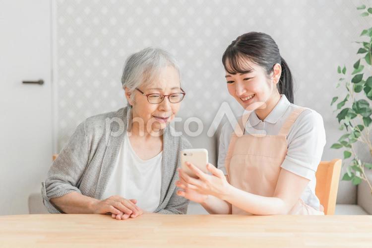 スマホを使う高齢者と女性スタッフ 高齢者,スマホ,スマートフォンの写真素材