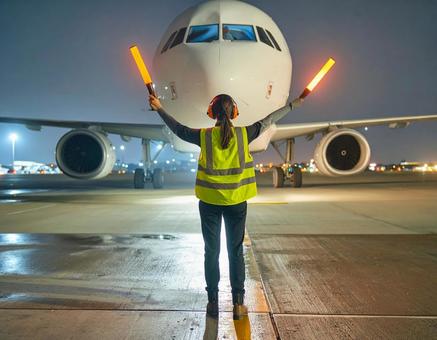 飛行機の到着を誘導する空港作業員 飛行機の到着を誘導する空港作業員の写真