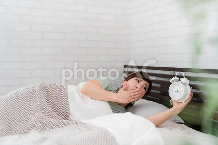 目覚まし時計で起きる女性（遅刻） 寝坊,遅刻,アラームの写真素材