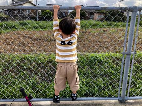 <素材>公園のフェンスを上ろうとする少年 <素材>公園のフェンスを上ろうとする少年 子供,男性,人物の写真素材