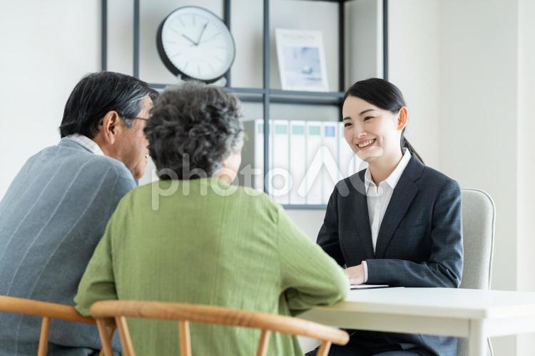 シニアの夫婦に説明するビジネスウーマン シニアの夫婦に説明するビジネスウーマン シニア,夫婦,説明の写真素材