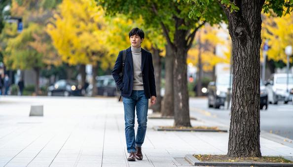 タートルネックを着て歩道を歩く若い男性 タートルネックを着て歩道を歩く若い男性の写真