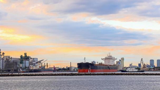 夕焼けの中タグボートに引かれる貨物船 貨物船,タグボート,工業地帯の写真素材