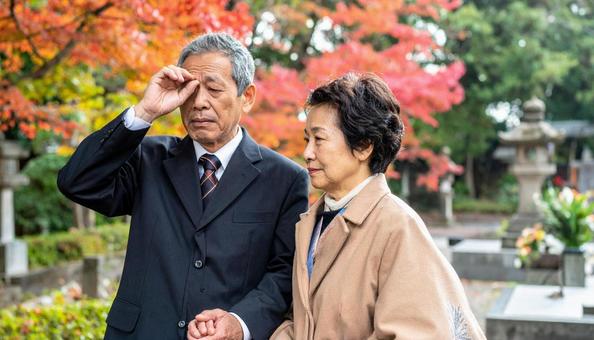お葬式・墓参りで目頭をおさえる老夫婦 お葬式・墓参りで目頭をおさえる老夫婦の写真