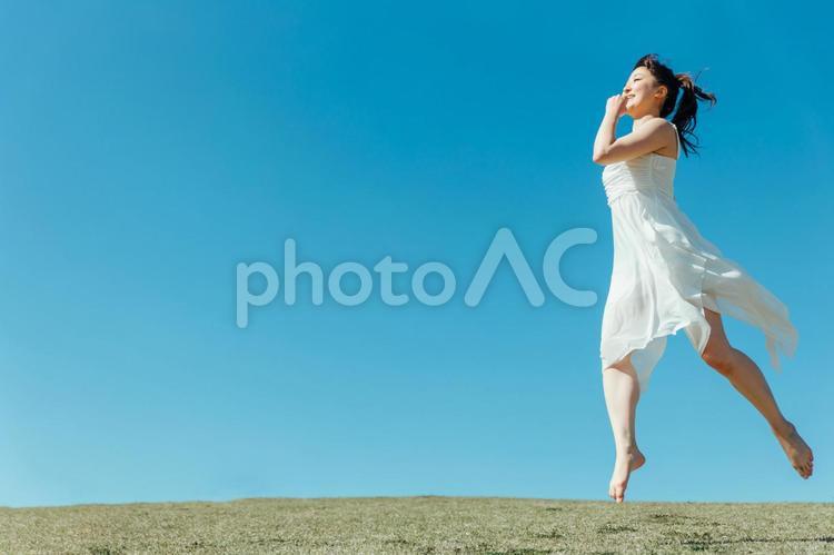 空と白いワンピースの踊る女性（ジャンプ） ジャンプ,跳ねる,飛ぶの写真素材