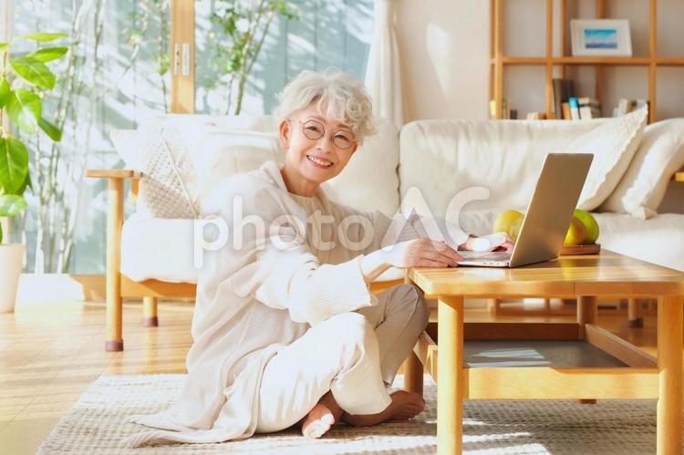 リビングの床に座ってノートパソコンを使うシニア女性 女性,高齢者,おばあちゃんの写真素材