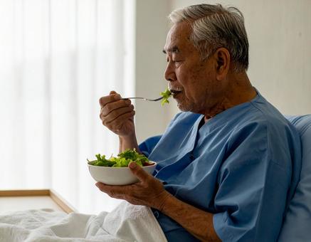 端座位で食事をするシニア男性の患者 端座位で食事をするシニア男性の患者の写真