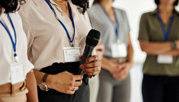 会議でマイクを持って意見を発表する女性 会議でマイクを持って意見を発表する女性の写真