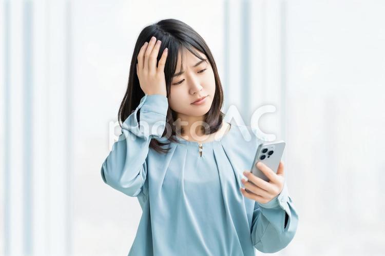 スマホを見て考える女性・ビジネスウーマン 女性,困る,考えるの写真素材