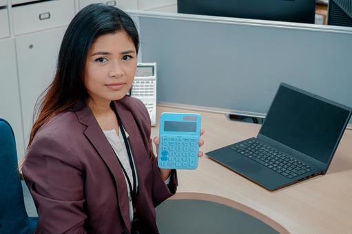 オフィスで電卓を見せるビジネスウーマン オフィスで電卓を見せるビジネスウーマン 女性,ビジネスウーマン,働く女性の写真素材
