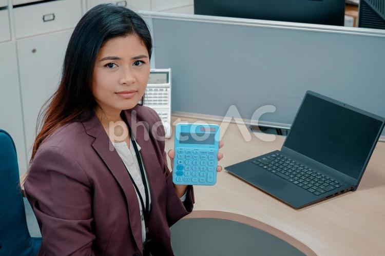 オフィスで電卓を見せるビジネスウーマン 女性,ビジネスウーマン,働く女性の写真素材