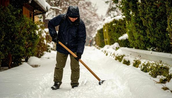 大雪が降った日の翌日の朝に雪かきする男性 大雪が降った日の翌日の朝に雪かきする男性の写真