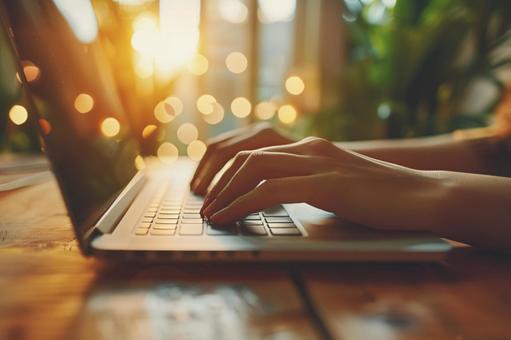 ノートパソコンと夕暮れの光の写真