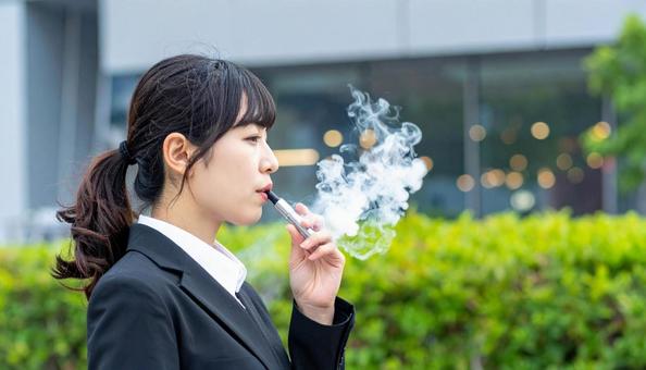 電子タバコを吸う若いビジネスウーマンの写真