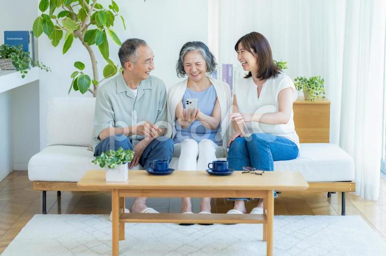 リビングでスマホを見るシニア夫婦と子供 シニア,夫婦,スマホの写真素材