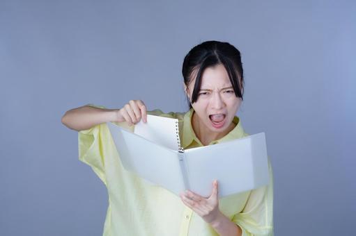 怒ってページをやぶる黄色い服の女性 女性,紙,ルーズリーフの写真素材