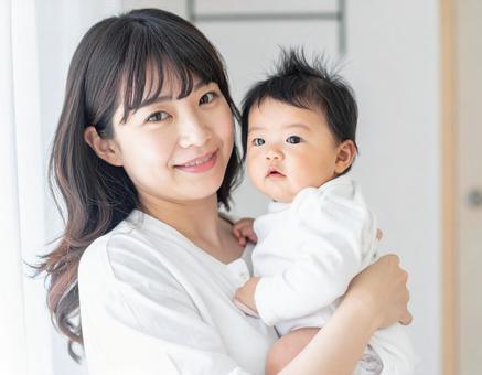 赤ちゃんを抱いて微笑んでいる若いお母さん 赤ちゃんを抱いて微笑んでいる若いお母さんの写真