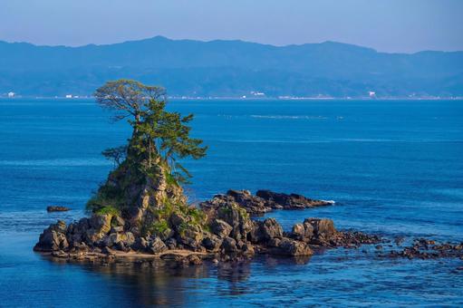 能登半島を背景に、青い富山湾に浮かぶ女岩 能登半島を背景に、青い富山湾に浮かぶ女岩 女岩,風景,富山湾の写真素材