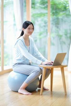 ボールに座り笑うパソコン作業中の女性 女性,バランスボール,笑顔の写真素材