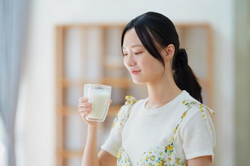 牛乳の入ったコップを見つめる女性の写真