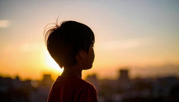 夕焼けの空を見つめる日本人の少年 夕焼けの空を見つめる日本人の少年の写真