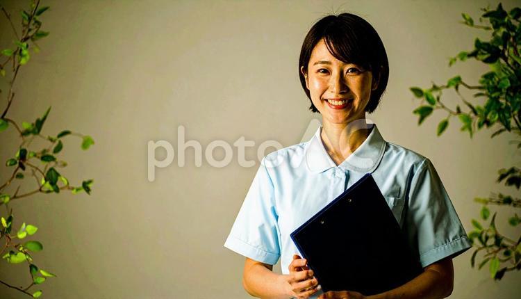 ファイルを抱える笑顔の日本人女性看護師 看護士,若い,白衣の写真素材