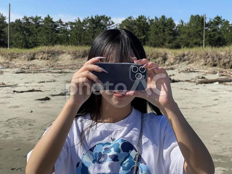 夏の砂浜でスマホで撮影する女性 女性,人,スマホの写真素材