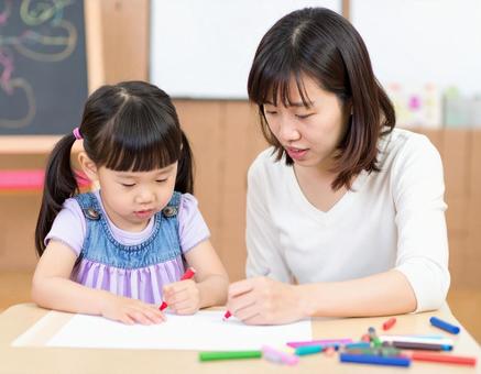 お絵描きをする子供と女性保育士 お絵描きをする子供と女性保育士の写真