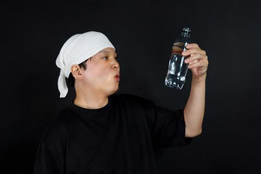 水の入ったペットボトルを見る男性 水の入ったペットボトルを見る男性の写真