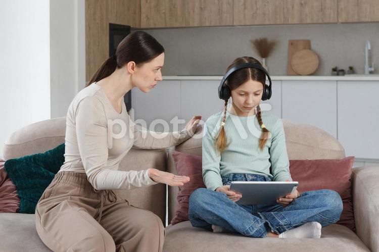 あぐらでタブレットを見て母親の説教を無視する娘 親子,女の子,女性の写真素材
