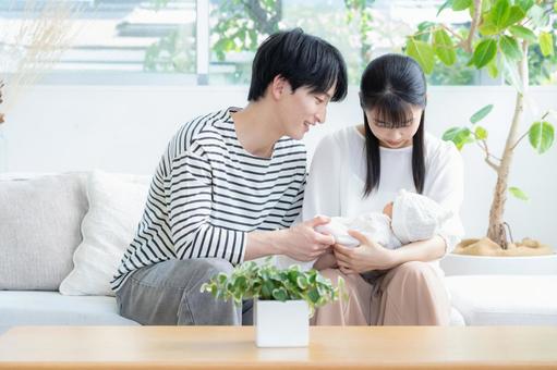 リビングで赤ちゃんを抱く若い家族 リビングで赤ちゃんを抱く若い家族 家族,親子,赤ちゃんの写真素材