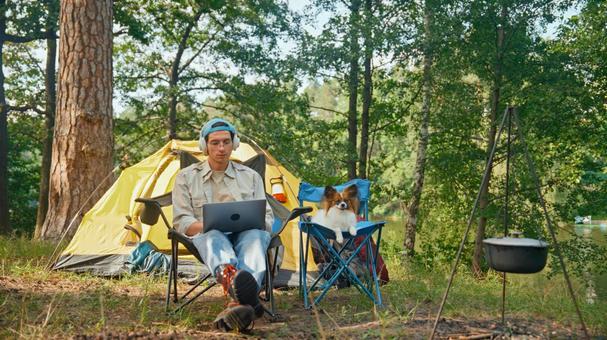 ノートPCで作業をする男性と横で座る犬 男性,外国人,犬の写真素材