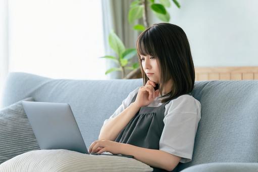 ソファに座ってパソコンを使う女性 ソファに座ってパソコンを使う女性 女性,ソファ,パソコンの写真素材
