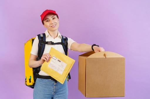 大きな手提げ段ボール箱とクッション封筒を持っている配達員の女性 配達,フードデリバリー,デリバリーの写真素材