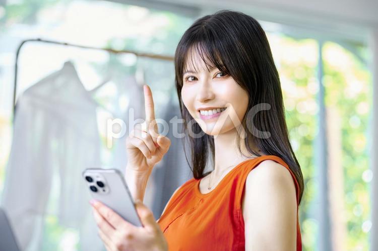 スマホを見る女性　指差し　窓際 スマホ,女性,主婦の写真素材