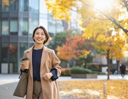 オフィス街を笑顔で歩く通勤中の女性 オフィス街を笑顔で歩く通勤中の女性の写真