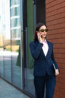 オフィスビルの外で電話しているサングラスを掛けたビジネスウーマン ビジネスウーマン,ビジネス,女性の写真素材