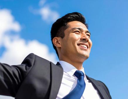青空の中で笑顔のビジネスマン 青空の中で笑顔のビジネスマンの写真