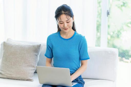 パソコンを操作する女性 女性,笑顔,ノートパソコンの写真素材