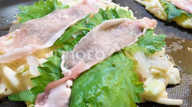 豚肉とシソをのせて焼き始める家庭のお好み焼き お好み焼き,シソ,粉物の写真素材