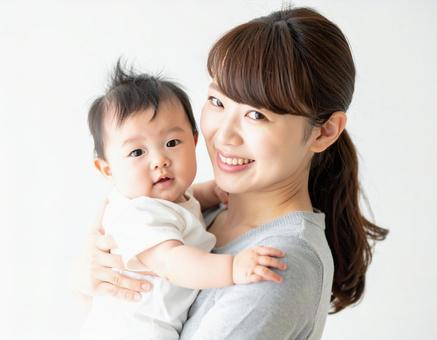 赤ちゃんを抱いて微笑んでいる若いお母さん 赤ちゃんを抱いて微笑んでいる若いお母さんの写真
