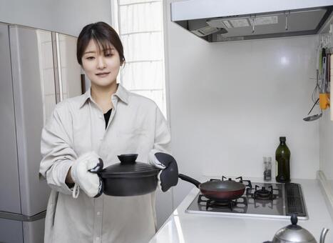 キッチンで鍋を運ぶ女性 キッチン,料理,主婦の写真素材