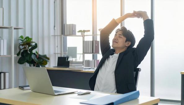 仕事が終わり達成感で背伸びをする社員 仕事が終わり達成感で背伸びをする社員の写真