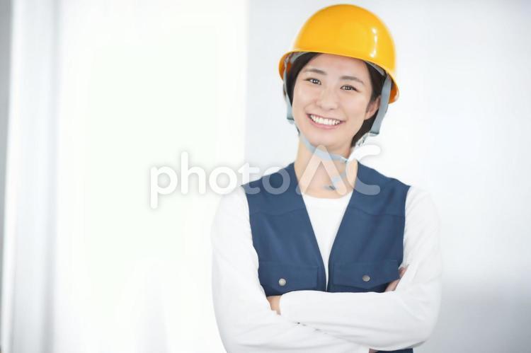 黄色いヘルメットで腕組みをする鳶服の女性 女性,日本人,鳶職の写真素材