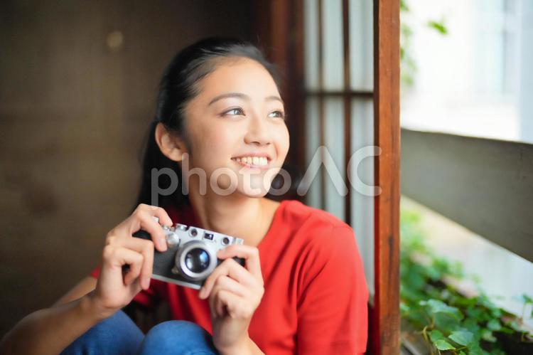 カメラを持ち外を見る女性 女性,カメラ,持つの写真素材