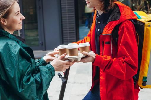 女性客にコーヒーを届けた男性配達員 配達,フードデリバリー,デリバリーの写真素材